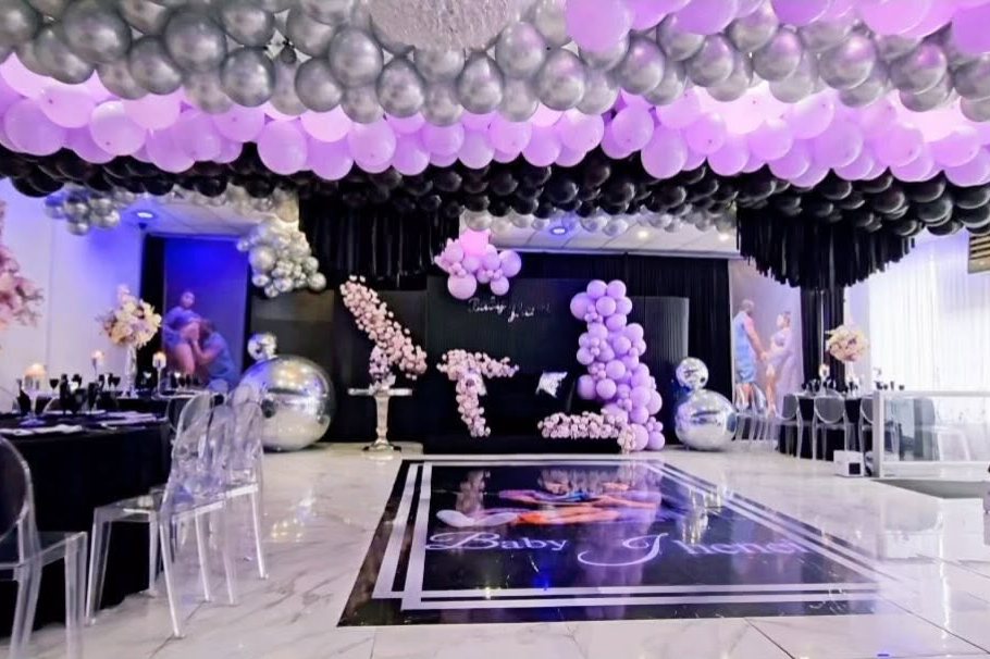 The event hall at La Mansion Venue set with black linens, ceiling balloons and a dance floor