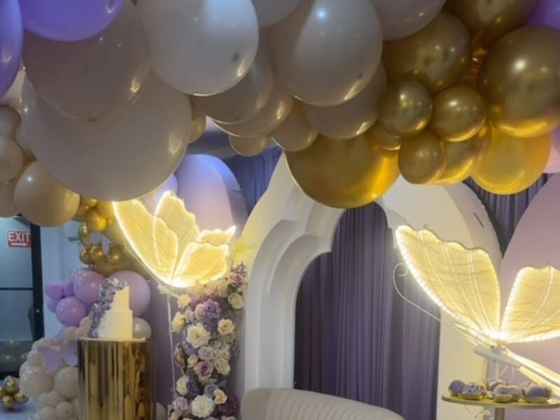 A lilac, white and gold lounge with butterfly lamps, gold pillars and a cake