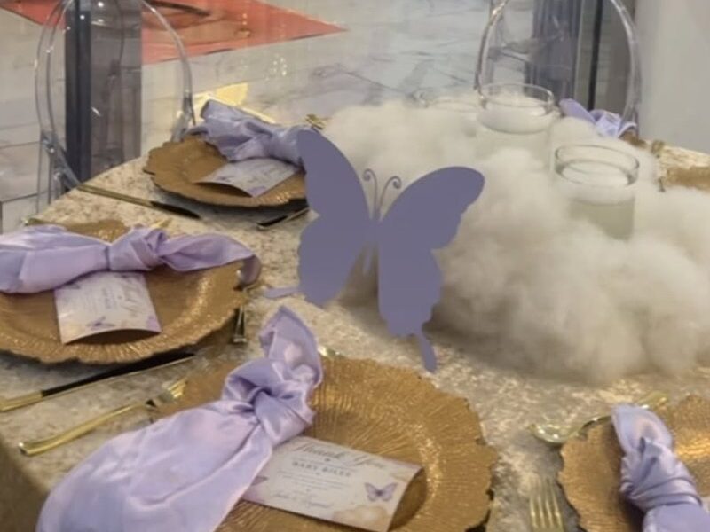 A table set with gold charger plates, lilac napkins and butterfly place cards